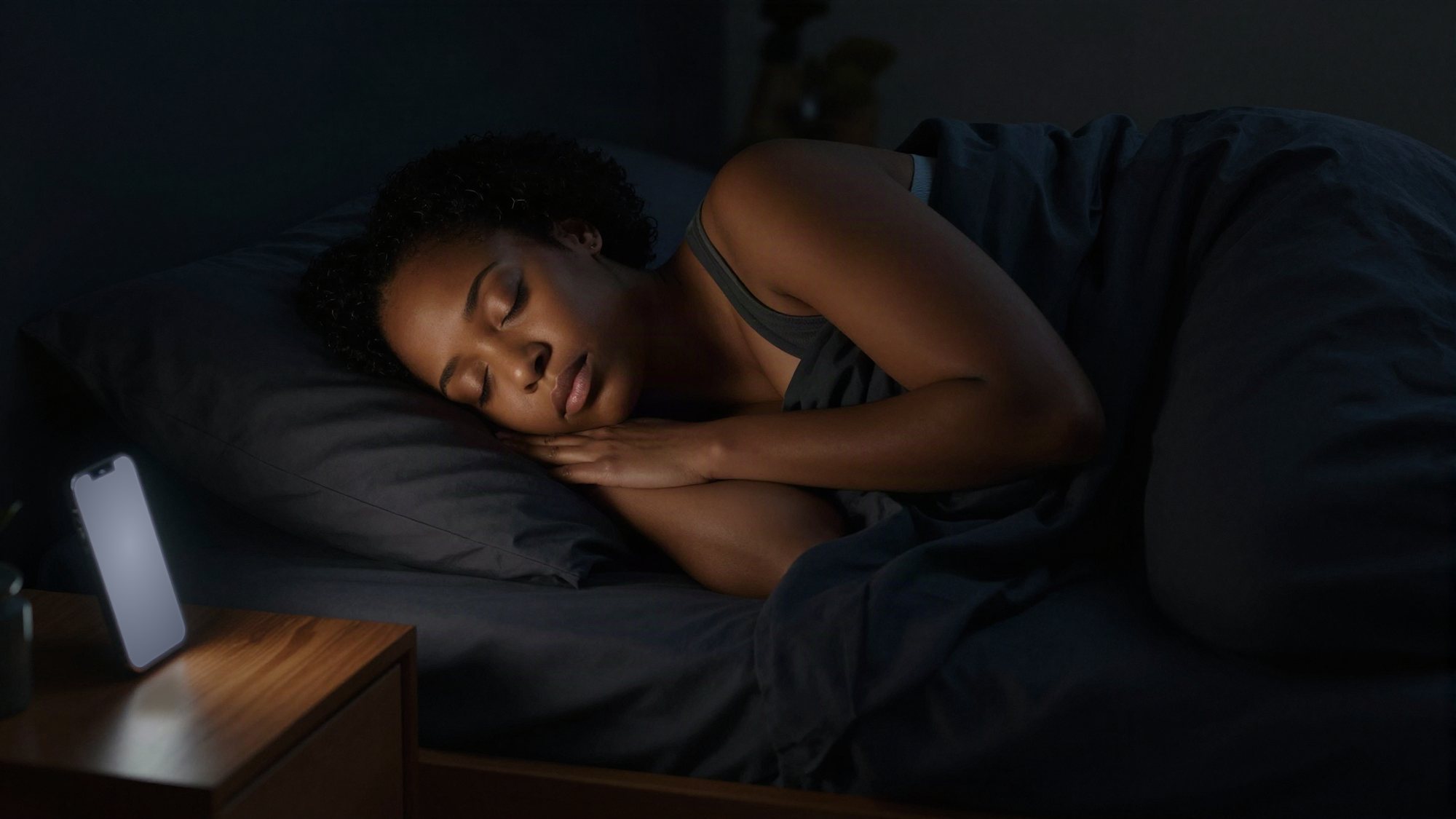A business owner asleep at night while her phone glows on the nightstand